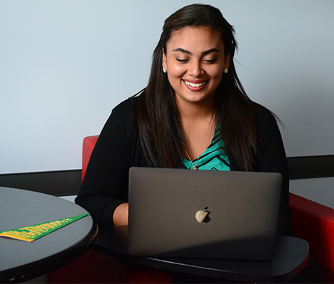 A student sitting in a conference room working on a laptop with a Ƶ pennant on the table